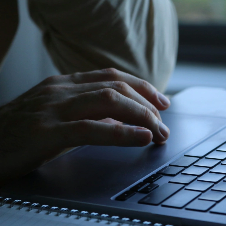 Lähikuva ihmisen kädestä käyttämässä kannettavaa tietokonetta